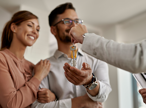 Consultor imobiliário a entregar as chaves de casa a um casal sorridente